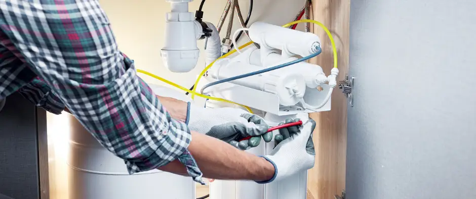 man installing a water filtration system under the kitchen sink